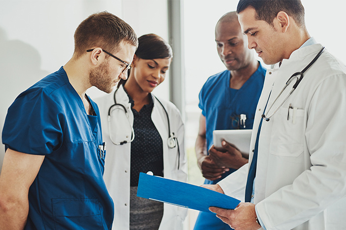 Medical-doctors-and-nurse-practitioners-discuss-paperwork-in-a-hallway